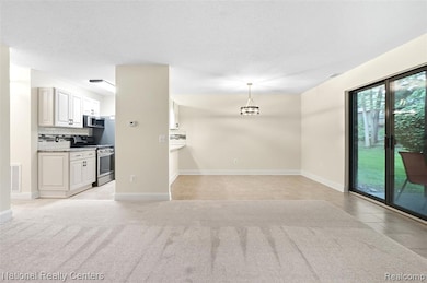 Unfurnished living room with light colored carpet, light tile patterned floors, and a textured ceiling