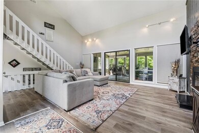 Living room featuring high vaulted ceiling, wood finished floors, a fireplace, and stairs