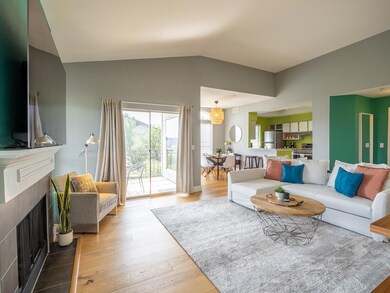 Living room with light wood finished floors, a fireplace, and vaulted ceiling