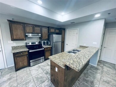 Kitchen with a peninsula, a sink, stainless steel appliances, dark brown cabinets, and under cabinet range hood