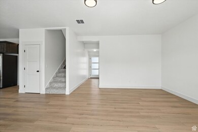 Unfurnished living room with light wood-type flooring and stairs