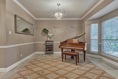Formal dining/living room with chair rail trim, wide base boards, sophisticated crown molding and updated lighting fixture.
