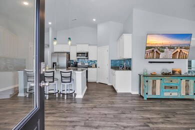 Kitchen featuring appliances with stainless steel finishes, a kitchen bar, white cabinets, decorative backsplash, and dark wood-type flooring