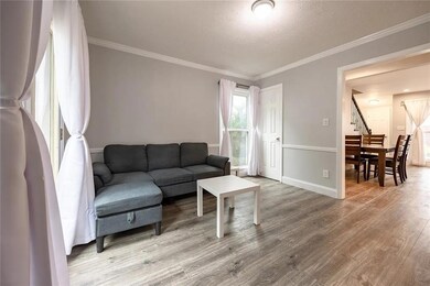 Living area with ornamental molding, light wood-style flooring, a textured ceiling, and stairway