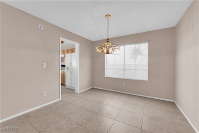 featuring a textured ceiling, a chandelier, and light tile patterned floors