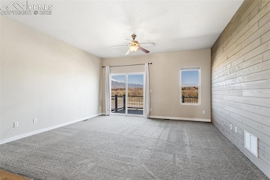 Spare room with baseboards, a ceiling fan, wood wa