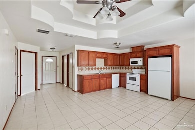 Kitchen featuring white appliances, tasteful backsplash, visible vents, and a tray ceiling