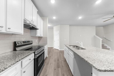 Kitchen featuring electric stove, a sink, under cabinet range hood, white cabinetry, and light wood-style flooring