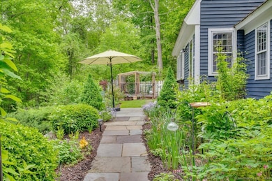 Pathway running in front of the house, through a mature perennial garden, leading to the front door.