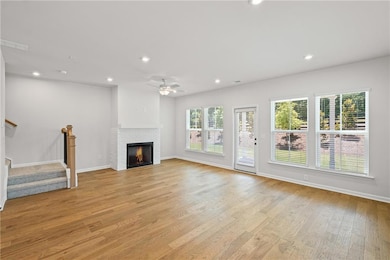 Unfurnished living room with recessed lighting, a brick fireplace, light wood-style floors, stairs, and ceiling fan