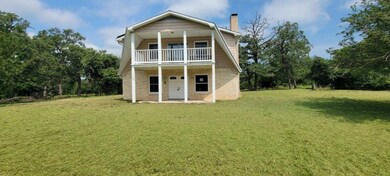 Front of house featuring a balcony and a yard