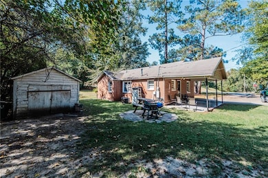 Back of property with a patio area, a yard, an outdoor structure, and a garage