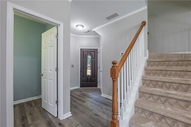 Entryway featuring wood finished floors, ornamental molding, and stairs