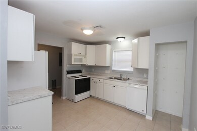 Kitchen with white cabinetry, sink, and white appl