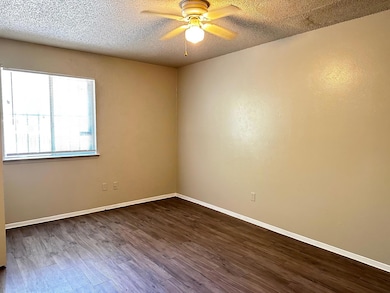 Spare room featuring dark wood-style floors, a textured ceiling, and ceiling fan