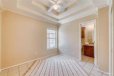 Unfurnished room featuring light tile patterned flooring, a tray ceiling, a ceiling fan, and ornamental molding