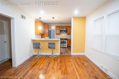 Kitchen with a kitchen breakfast bar, dark wood finished floors, light countertops, and pendant lighting