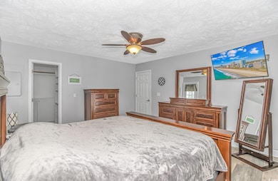 Bedroom featuring a ceiling fan, a closet, a textu