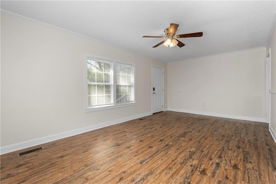 Spare room featuring dark wood-style floors, a textured ceiling, crown molding, and ceiling fan