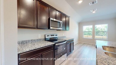 Kitchen with appliances with stainless steel finishes, dark brown cabinetry, light wood finished floors, light stone counters, and recessed lighting