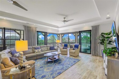 Living area featuring a raised ceiling, ceiling fan, and light wood finished floors