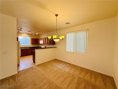Kitchen featuring dark countertops, pendant lighting, light colored carpet, brown cabinetry, and light tile patterned floors