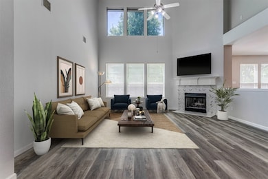 Spacious living room with soaring ceiling, double stacked windows giving amazing natural light and fireplace with gaslogs and striking tile work. The flow of the room is great for entertaining as you have easy access to the kitchen and the nook. (virtually staged to show potential)