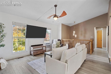 Living room with a ceiling fan, light wood-type flooring, lofted ceiling, and cooling unit