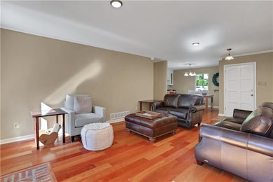 Living area featuring light wood finished floors, ornamental molding, and a chandelier