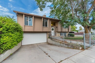 Split foyer home featuring an attached garage, driveway, a chimney, and brick siding