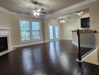 Unfurnished living room with healthy amount of natural light, dark wood-style floors, a premium fireplace, a ceiling fan, and beam ceiling