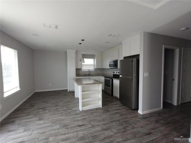 Kitchen featuring appliances with stainless steel finishes, open shelves, a sink, and white cabinets