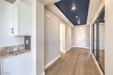 Corridor featuring light wood-type flooring, baseb