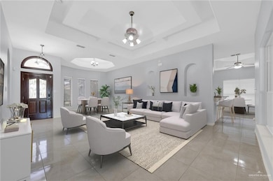 Living room featuring a tray ceiling, ceiling fan, and light tile patterned floors