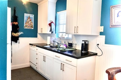 Kitchen with a wainscoted wall, white cabinetry, white appliances, and tile countertops