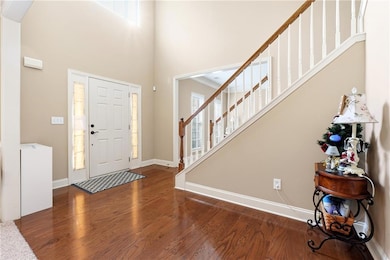 Foyer entrance featuring dark wood finished floors, stairs, and a towering ceiling
