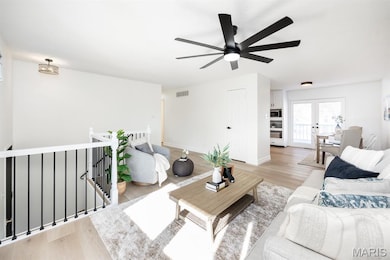 Living room with light wood-style floors, french doors, and a ceiling fan