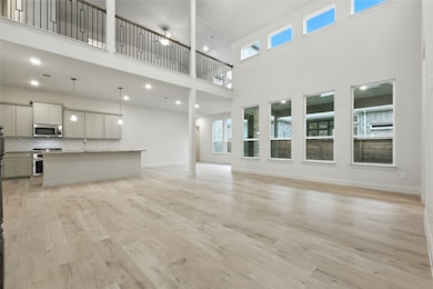 Unfurnished living room featuring light wood-type flooring, a towering ceiling, and recessed lighting