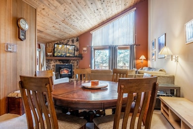 Carpeted dining space featuring high vaulted ceiling and wooden ceiling