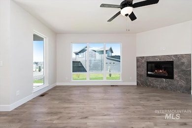 Unfurnished living room with light wood finished floors, a fireplace, and ceiling fan
