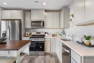 Kitchen with white cabinets, gas oven/range, microwave over cooktop, and quartz countertops.  Photos is of model home. Colors and options may vary. Ask Sales Agent for details.
