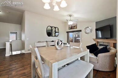 Dining space featuring dark wood-style flooring, a chandelier, ceiling fan, baseboards, and a fireplace