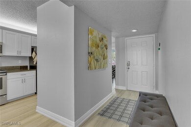 Hallway with a textured ceiling and light hardwood