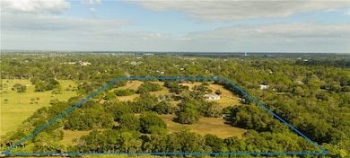 Aerial view of property and surrounding area featuring property boundaries highlighted and a heavily wooded area
