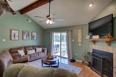 Living area featuring wood finished floors, a tiled fireplace, a textured ceiling, and a ceiling fan