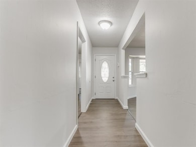 Doorway featuring a textured ceiling and light har