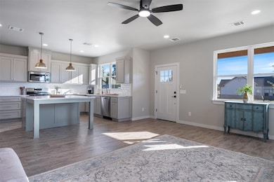 Kitchen featuring light countertops, a breakfast bar area, gray cabinets, wood finished floors, and recessed lighting