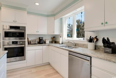 Kitchen with a sink, backsplash, white cabinetry, 