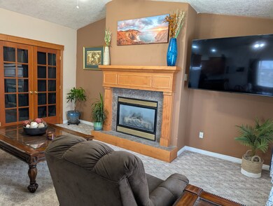 Carpeted living room with a textured ceiling, a fireplace, and lofted ceiling