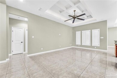 Unfurnished room with beamed ceiling, coffered ceiling, light tile flooring, ceiling fan, and a raised ceiling
